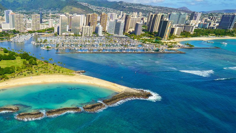 Aerial of the Ala Wai Harbor, Magic Island and the Honolulu skyline with turquoise reef water, Oahu, Hawaii