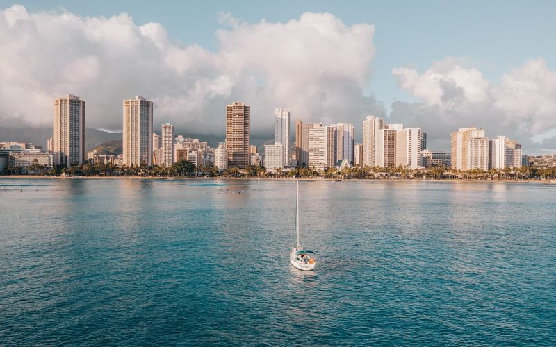 A boat under sail off Waikiki with the Honolulu skyline and Diamond Head behind it, Oahu, Hawaii