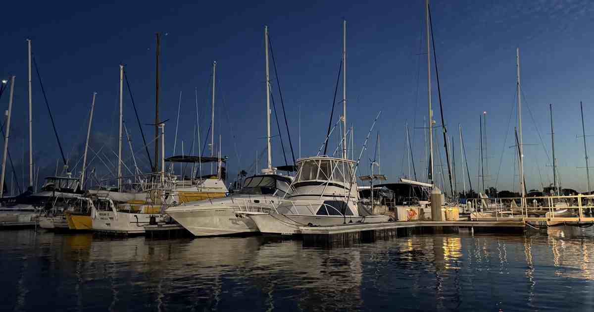 Powerboats and sailboats tied up along the dock at an Oahu harbor at blue hour, Honolulu, Hawaii