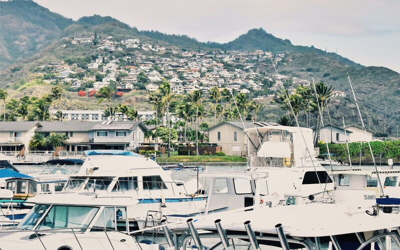 Powerboats docked in an Oahu marina with a green Hawaii Kai hillside behind