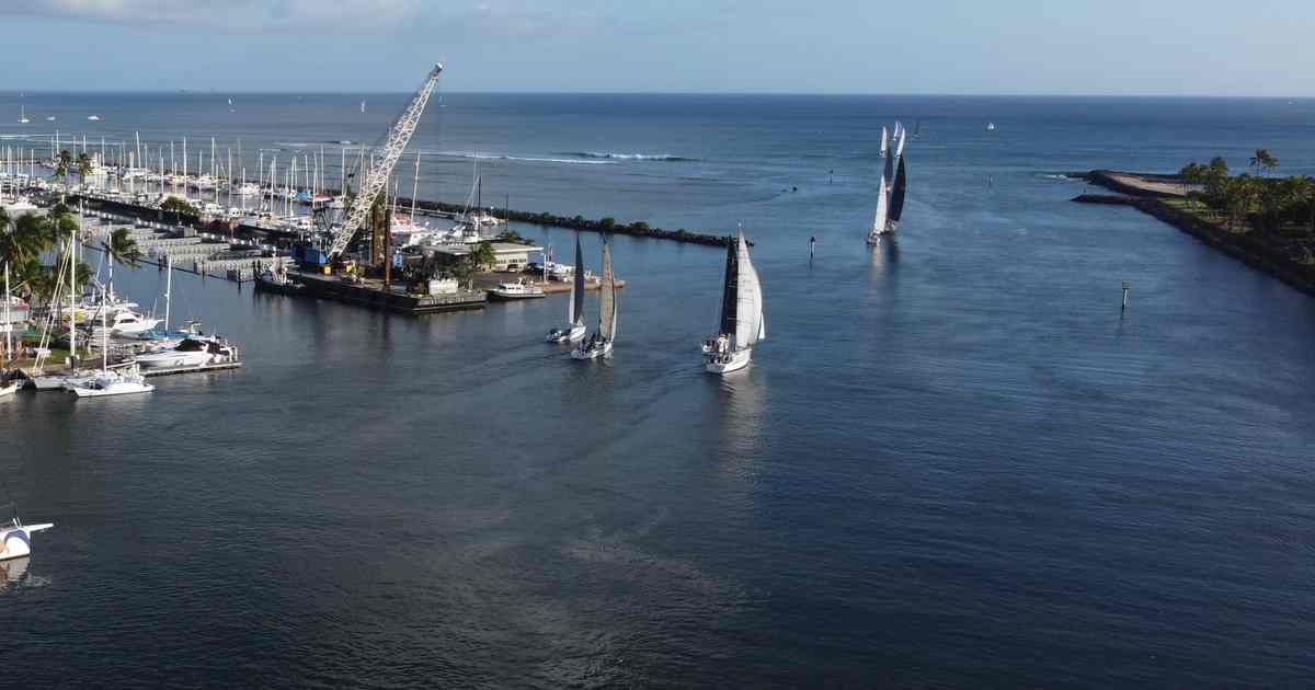 Aerial view of the Ala Wai Boat Harbor entrance with sailboats heading to sea past the breakwater, Honolulu, Oahu