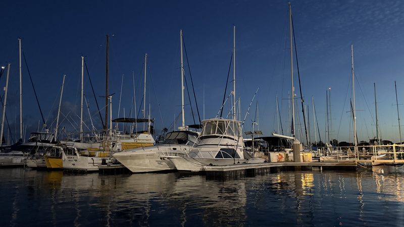 Boats and sailboat masts at an Oahu marina at dusk with a sunset glow, Honolulu, Hawaii